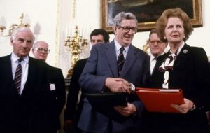 La primera ministra Margaret Thatcher y Taoiseach Garret Fitzgerald se dan la mano después de firmar el Acuerdo Anglo-Irlandés. Peter Barry está a la izquierda.