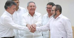 El presidente Santos (izquierda) y el líder de las FARC “Timochenko” se dan la mano tras reunión facilitada por Raúl Castro (centro)